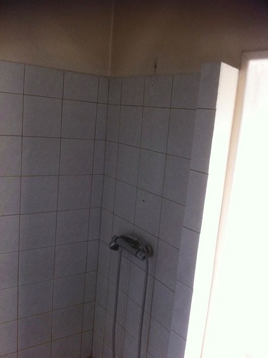 Une salle de bain avec carrelage blanc et pommeau de douche.