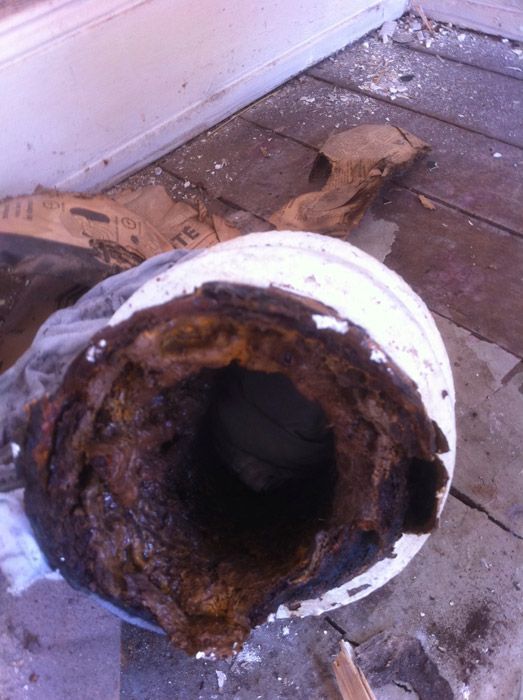 Un seau blanc avec un trou dedans est posé sur un plancher en bois.