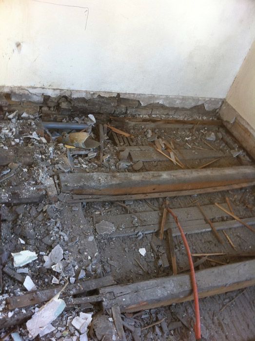 Une pièce avec beaucoup de bois cassé et de béton sur le sol.