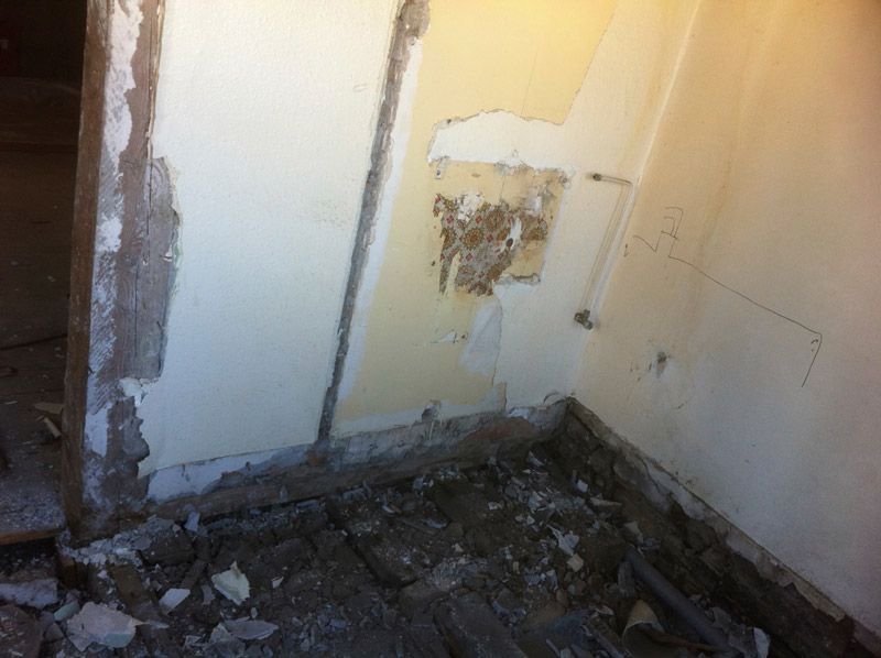 Une pièce avec un mur cassé et beaucoup de saleté sur le sol.