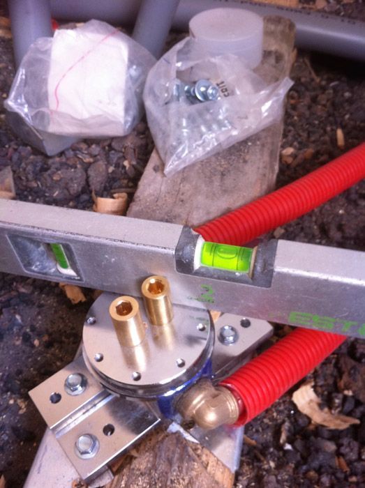 Un niveau est posé sur un morceau de bois à côté d'un tuyau rouge