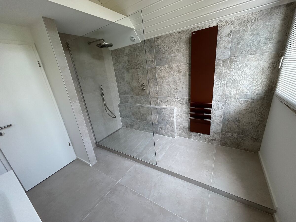 Une salle de bain avec douche à l'italienne et radiateur.