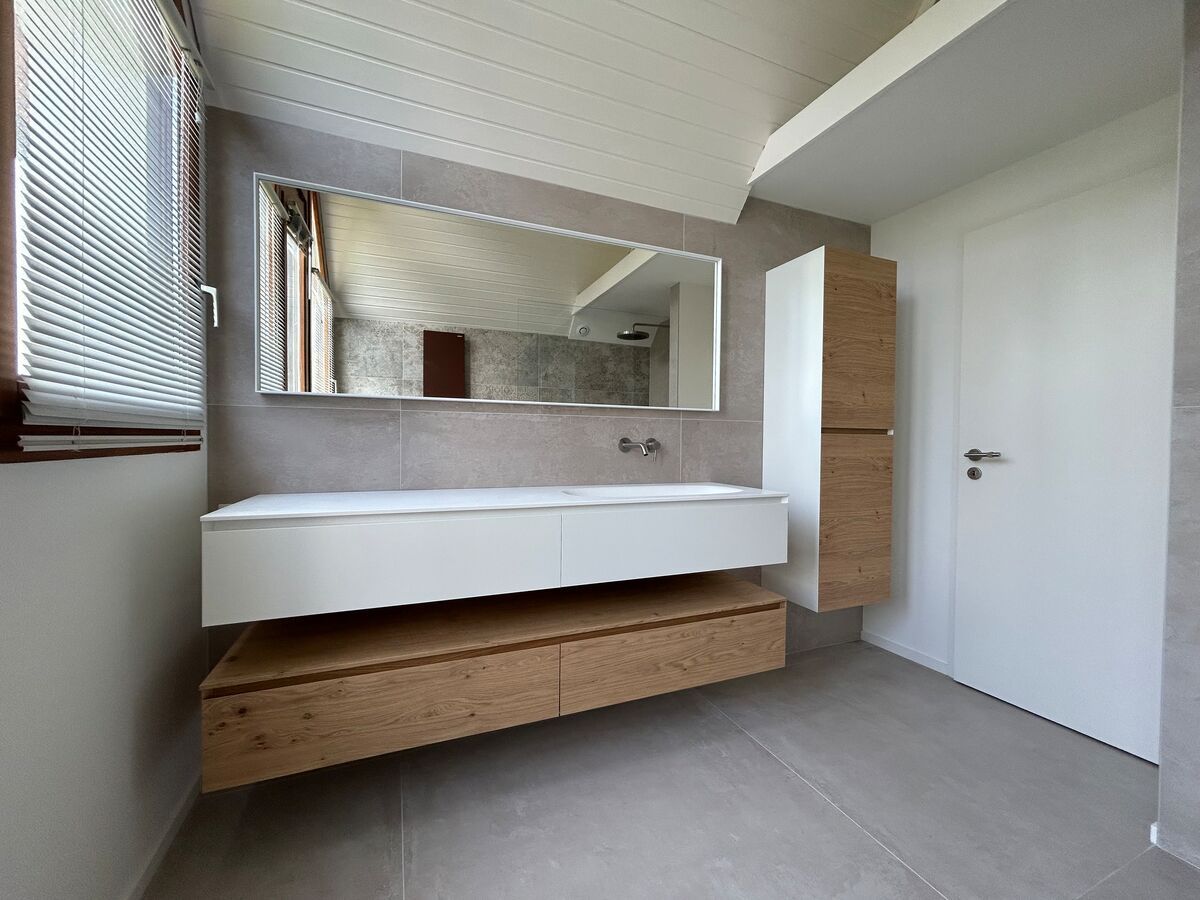 Une salle de bain avec un lavabo, un miroir et des armoires.