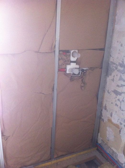 Une pièce avec un mur en carton et des fils électriques qui en sortent.