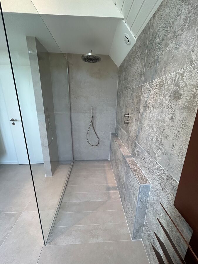 Une salle de bain avec douche à l'italienne et pommeau de douche.