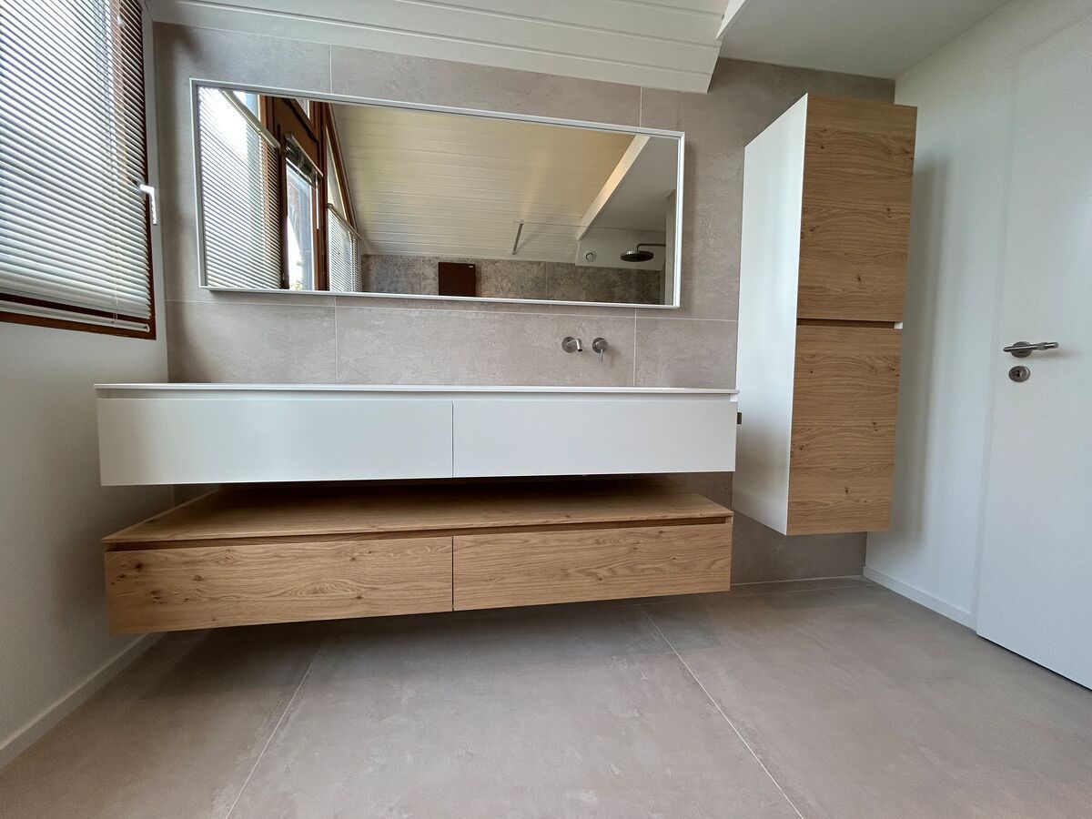 Une salle de bain avec un lavabo, un miroir et des armoires.