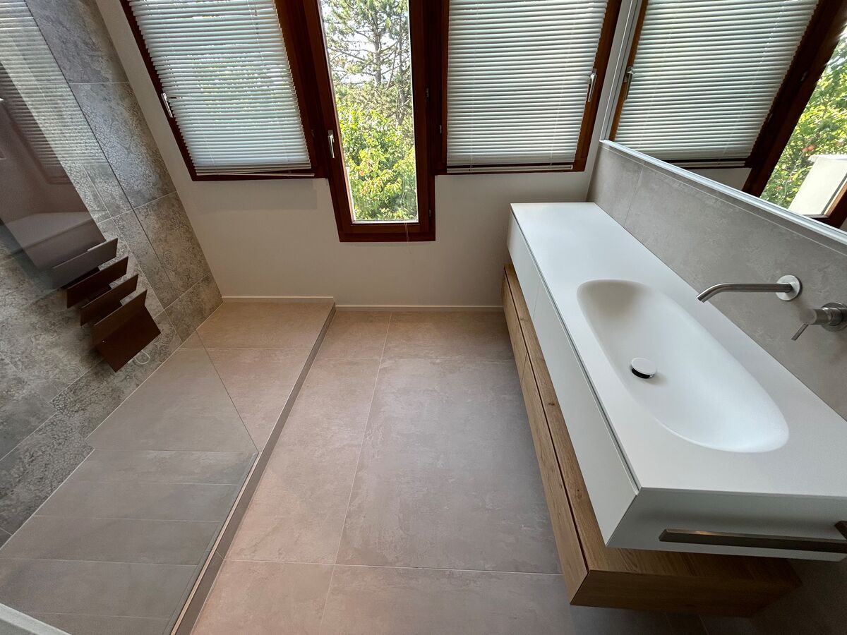 Une salle de bain avec un lavabo et une fenêtre avec des stores