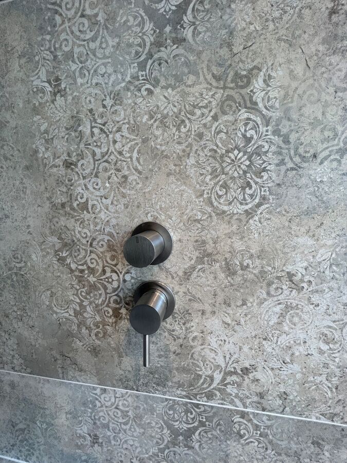 Un gros plan d'une pomme de douche sur un mur carrelé.