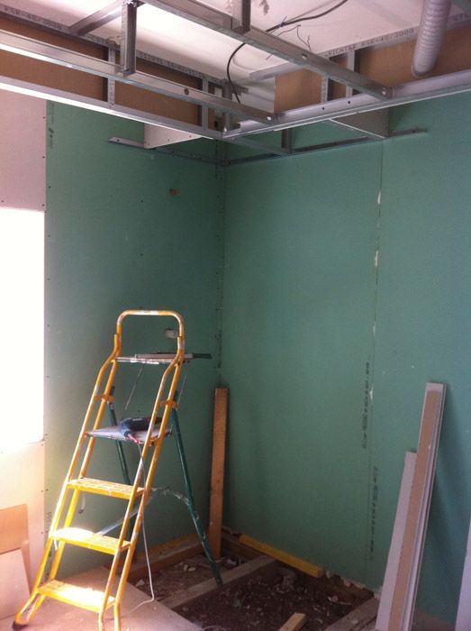 Une échelle jaune se trouve dans une pièce aux murs verts