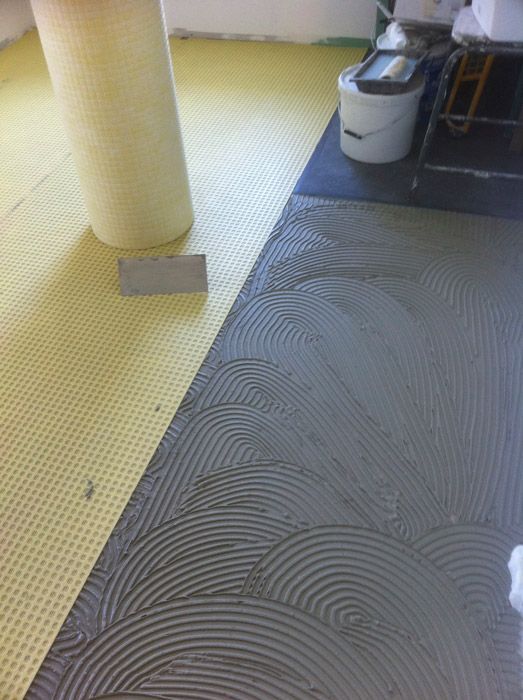 Un sol en carrelage gris et jaune est en cours d'installation dans une pièce.