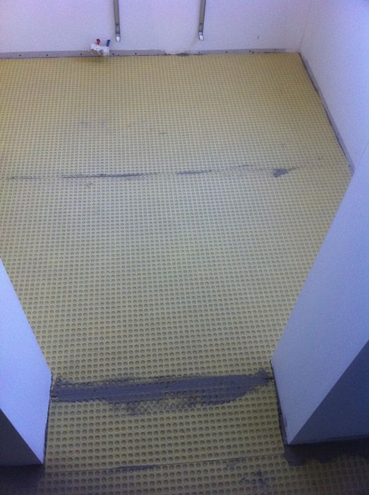 Une pièce avec un sol en carrelage jaune et des murs blancs.