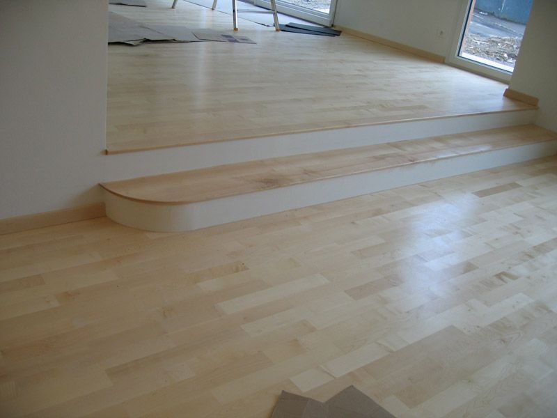 Un plancher en bois avec des escaliers qui y mènent dans une pièce.