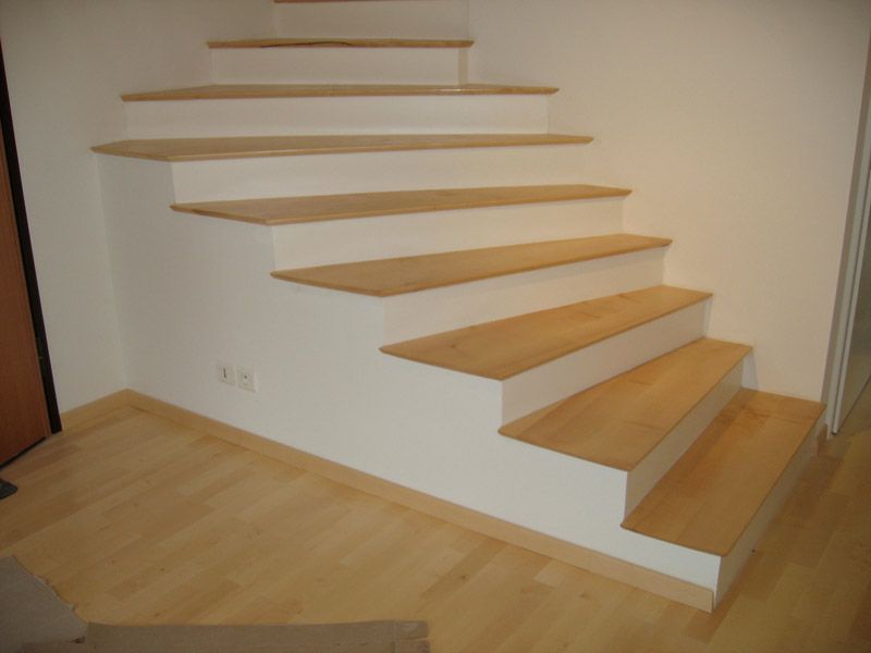 Un escalier avec des marches en bois et des murs blancs