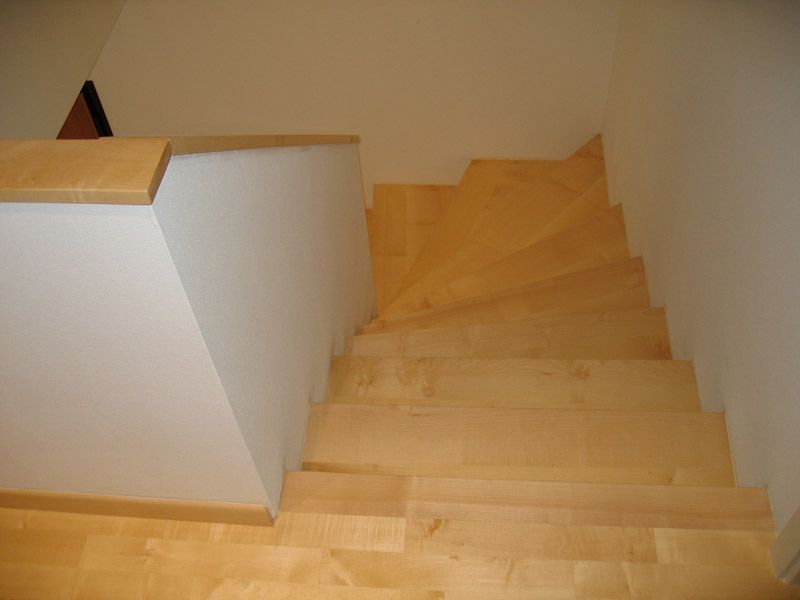 Un escalier en bois avec un mur blanc derrière