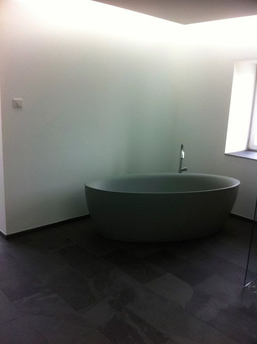 Une baignoire est placée dans une salle de bain à côté d'une fenêtre.