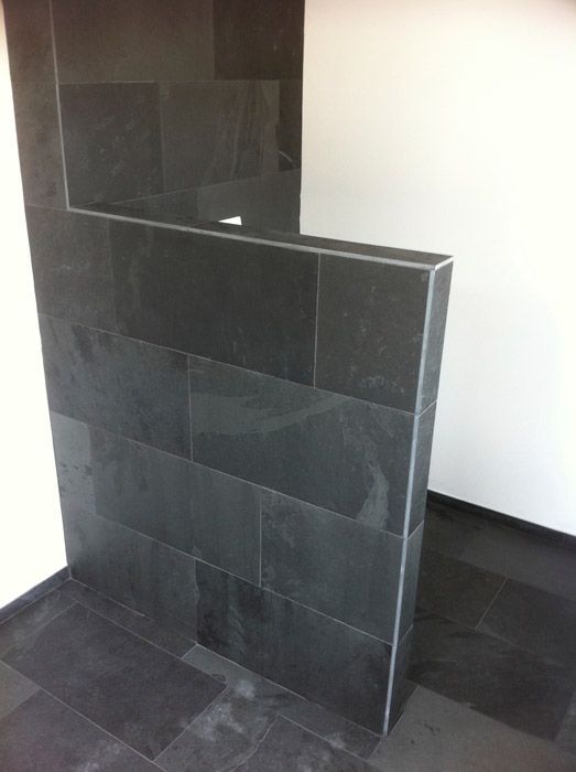 Une pièce avec du carrelage noir et un mur blanc