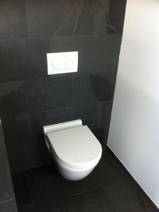 Une toilette blanche est montée sur un mur noir