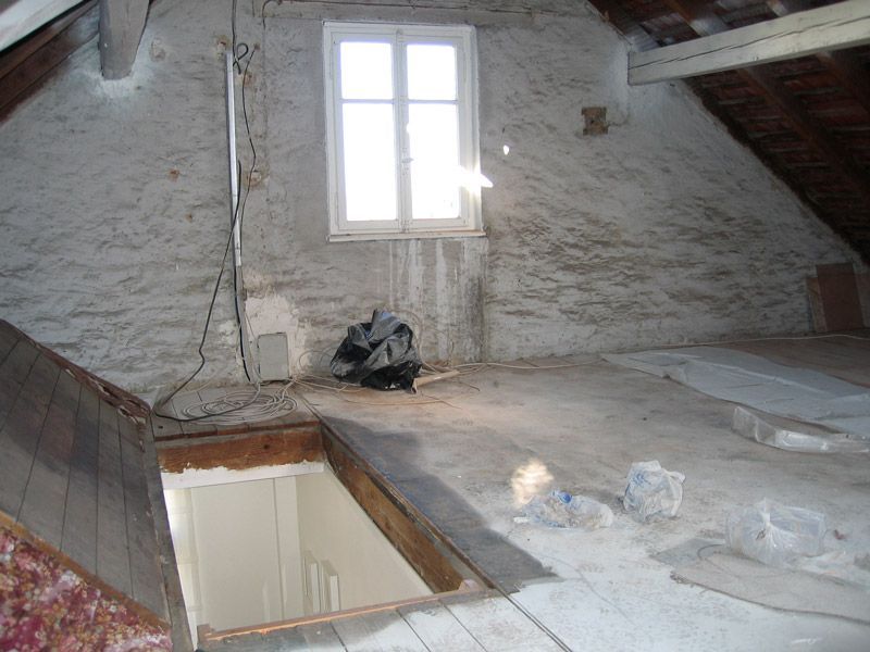 Un grenier vide avec une fenêtre et un escalier