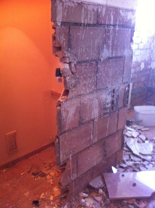 Un mur de briques est en train d'être démoli dans une pièce.