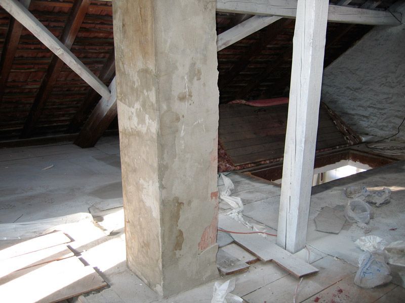 Une colonne en béton dans une pièce avec des poutres en bois