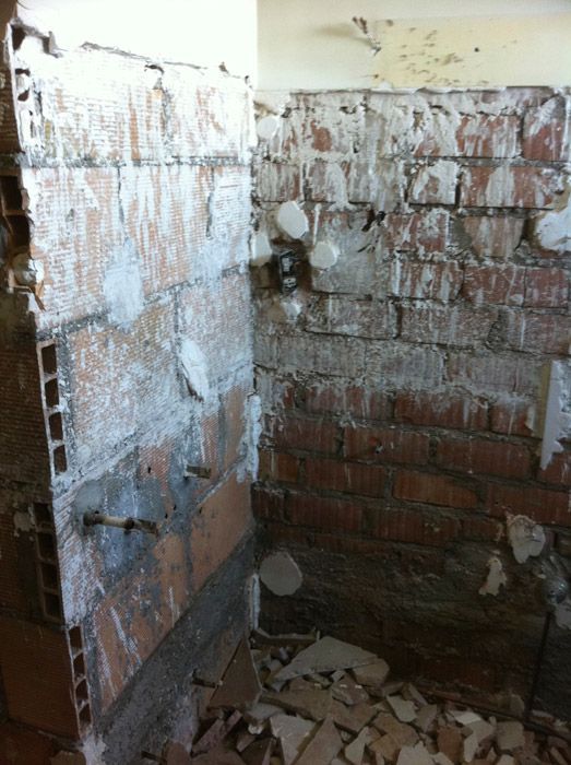 Un mur de briques est en train d'être démoli dans une salle de bain