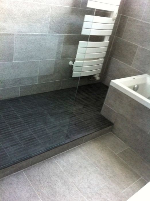 Une salle de bain avec douche à l'italienne, lavabo et porte-serviettes.