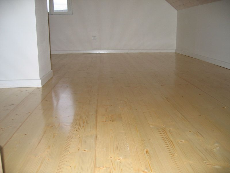 Une pièce vide avec un plancher en bois et des murs blancs.