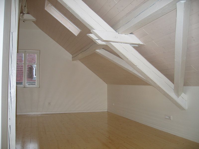 Une pièce vide avec un plafond incliné et une fenêtre