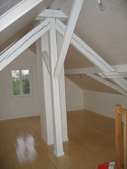 Une pièce vide avec un plancher en bois et des poutres blanches