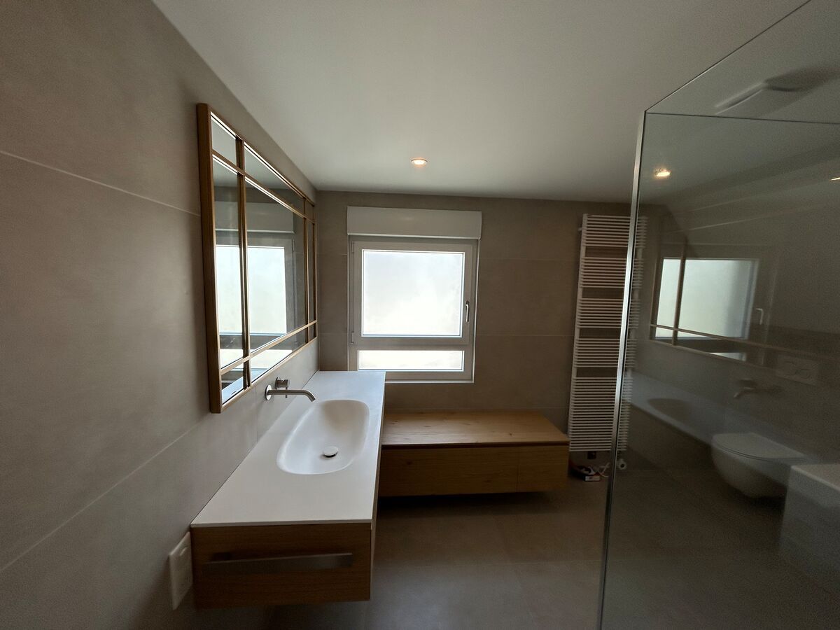 Une salle de bain avec un lavabo, un miroir et une fenêtre