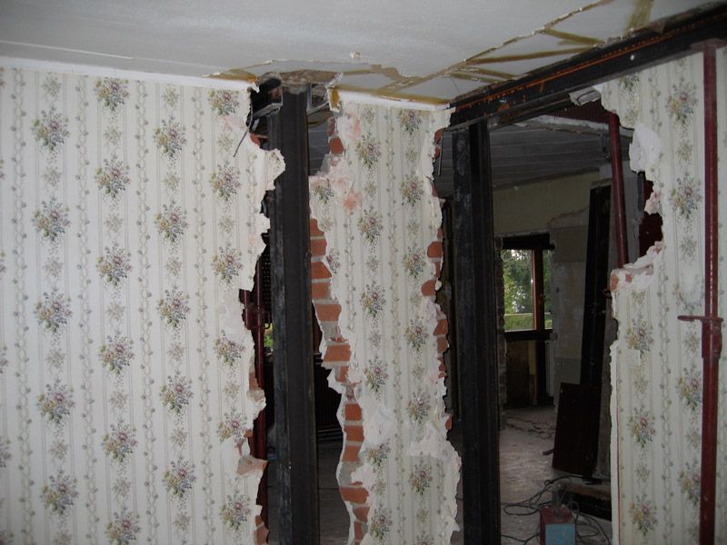 Une pièce avec un trou dans le mur et un papier peint à fleurs