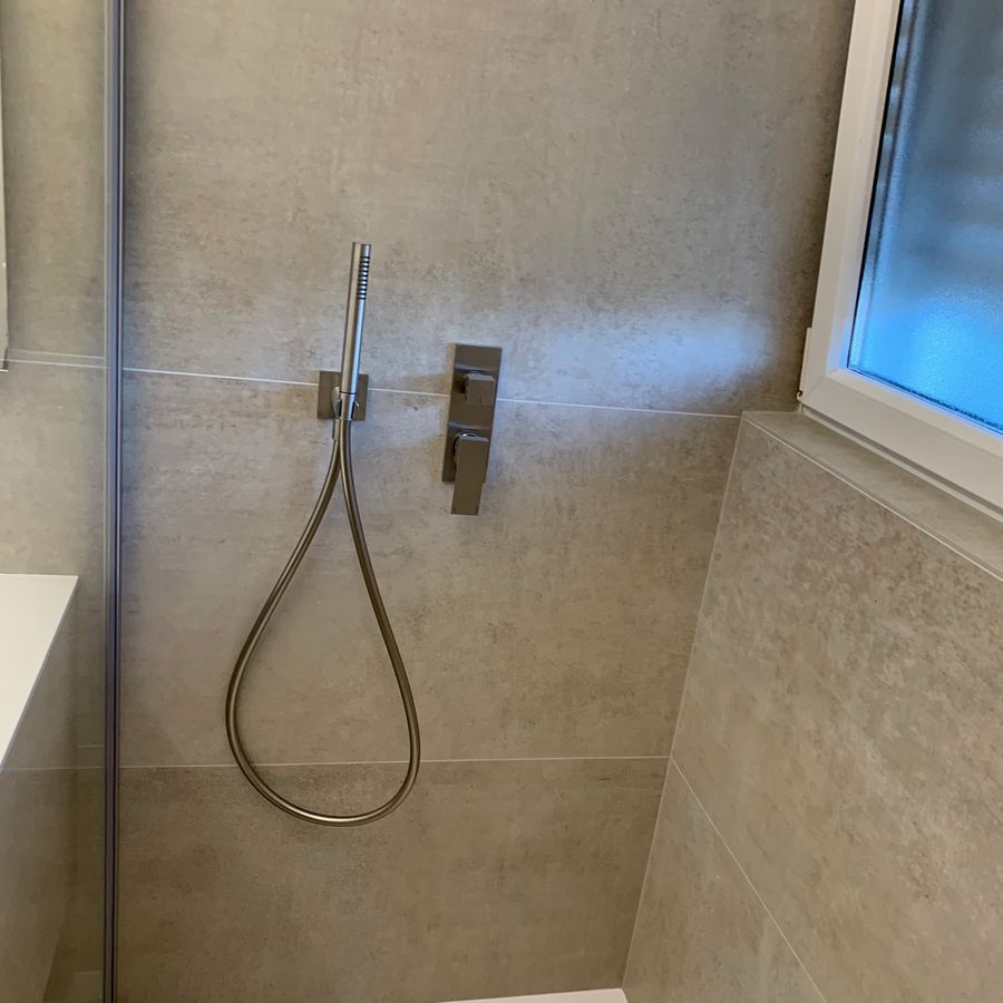 Une salle de bain avec une pomme de douche et une fenêtre