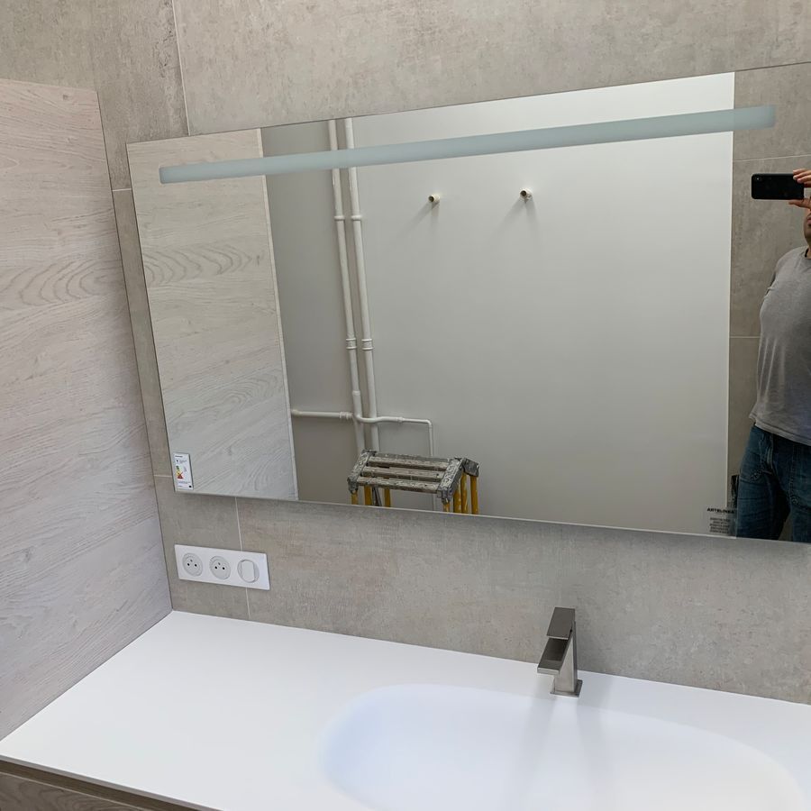 Un homme prend une photo de lui-même dans un miroir de salle de bain.