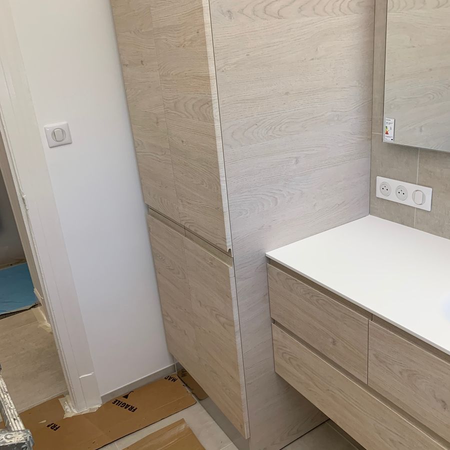 Une salle de bain avec un lavabo, des armoires et un miroir.