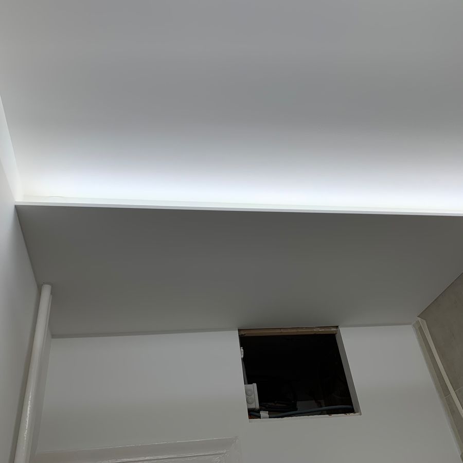 Un plafond blanc avec une lumière qui en sort et un trou dans le mur.
