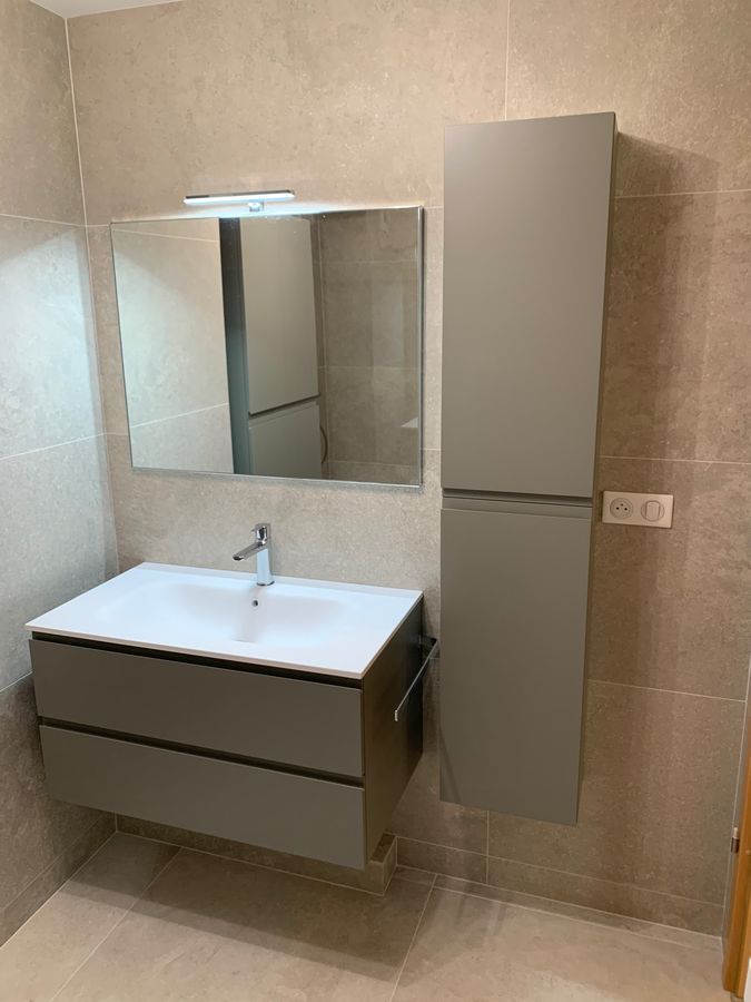 Une salle de bain avec un lavabo, un miroir et des armoires.