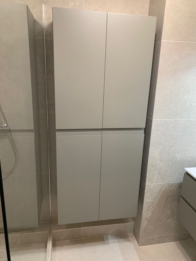 Une salle de bain avec un meuble blanc et une cabine de douche.