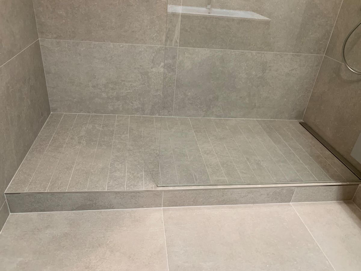 Une salle de bain avec douche à l'italienne et sol carrelé.