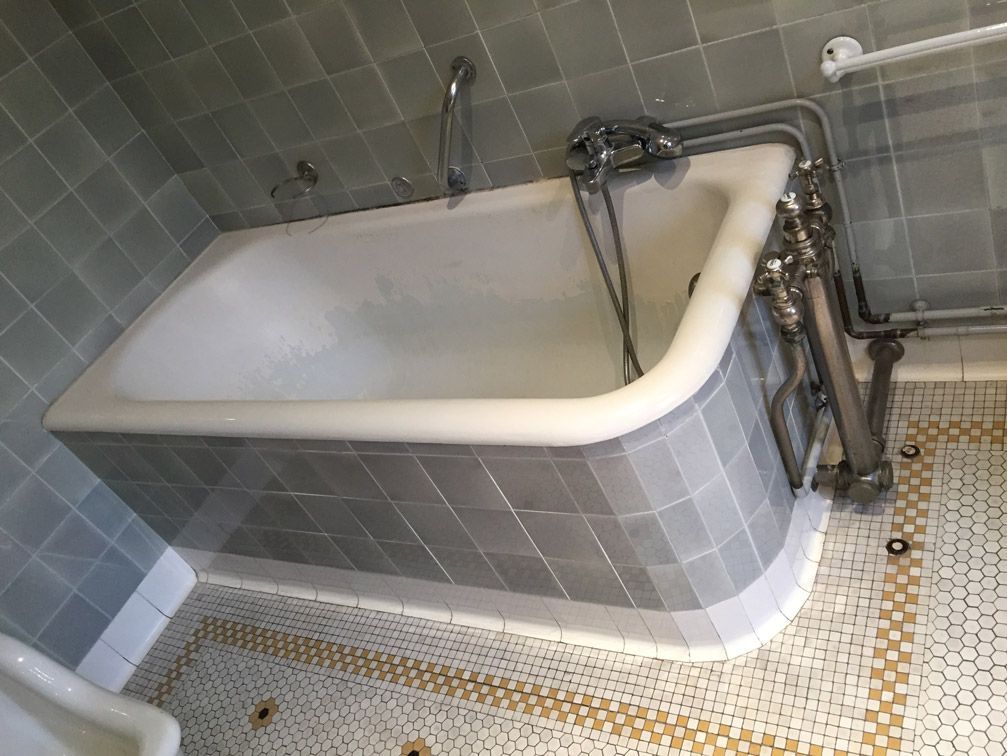 Une baignoire est placée dans une salle de bain à côté d'un urinoir.