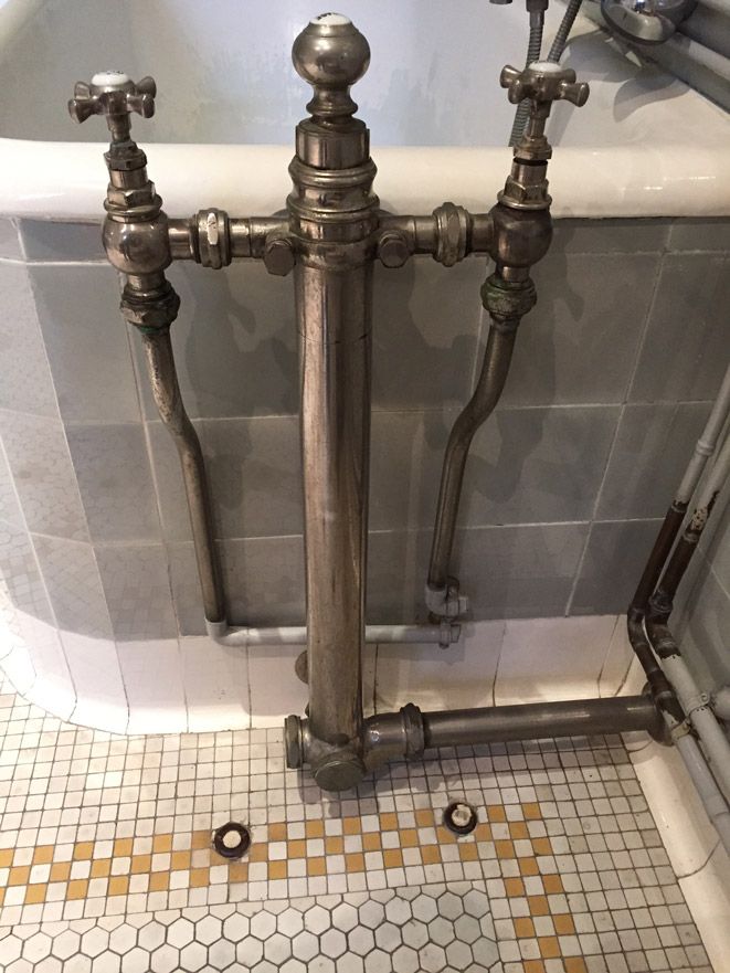 Une salle de bain avec une baignoire et un robinet au sol.