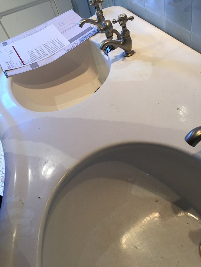 Un lavabo de salle de bain avec deux robinets et un morceau de papier dessus.
