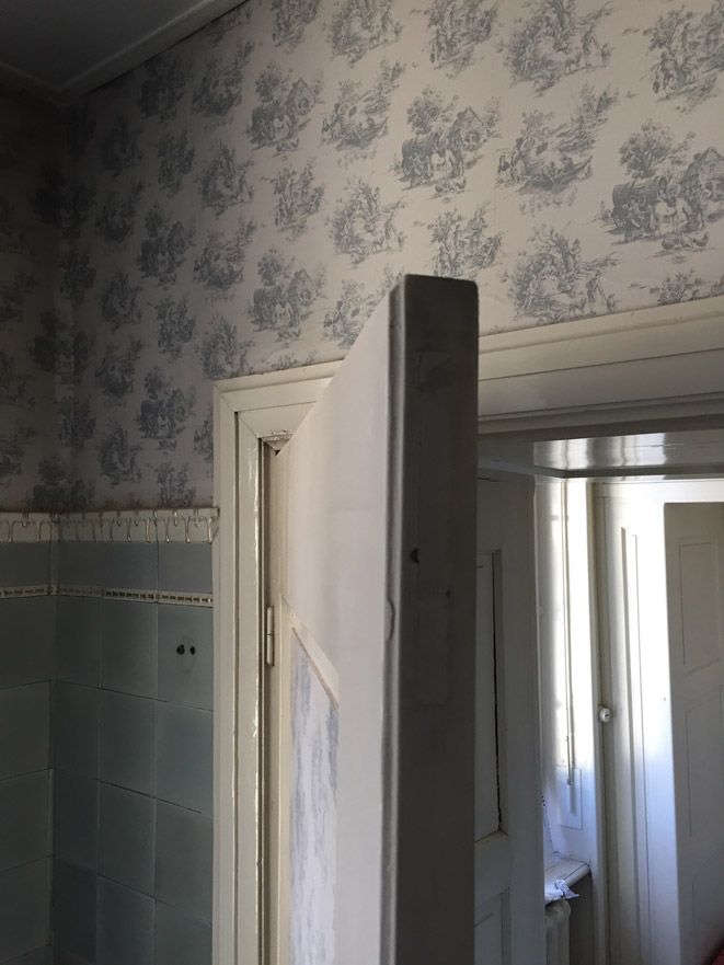 Une porte dans une pièce avec un papier peint floral sur le mur