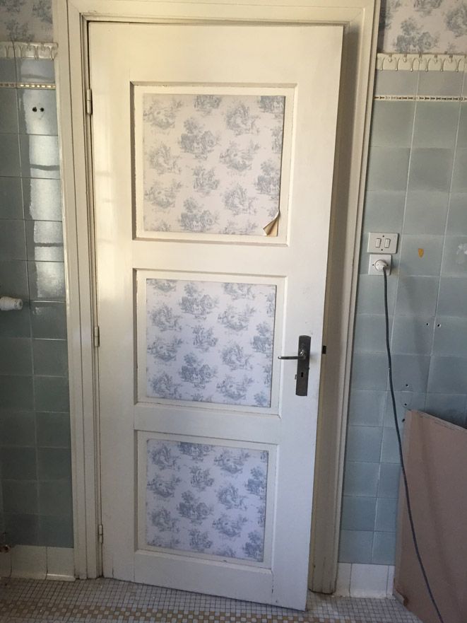 Une porte blanche avec un motif floral se trouve dans une salle de bain.