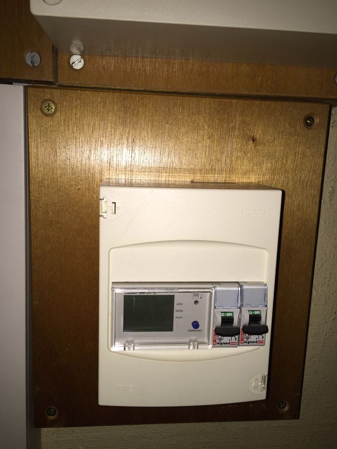 Une boîte blanche avec un affichage numérique est posée sur un mur en bois.