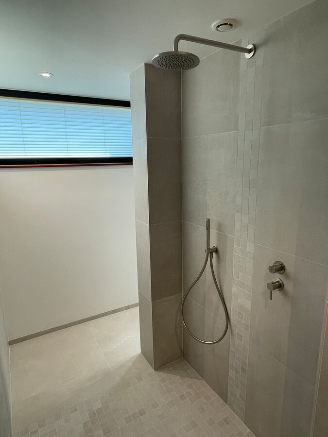 Une salle de bain avec douche à l'italienne et fenêtre.