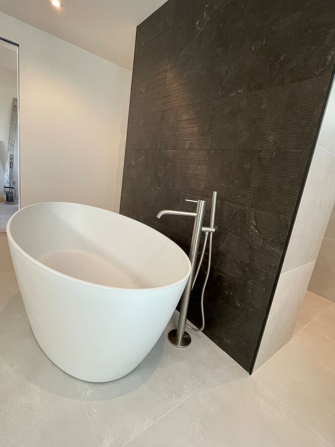 Une baignoire blanche dans une salle de bain à côté d'un mur noir