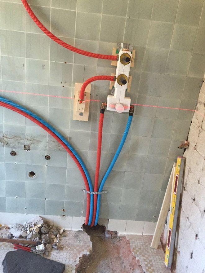 Un tas de tuyaux sont reliés à un mur dans une salle de bain.