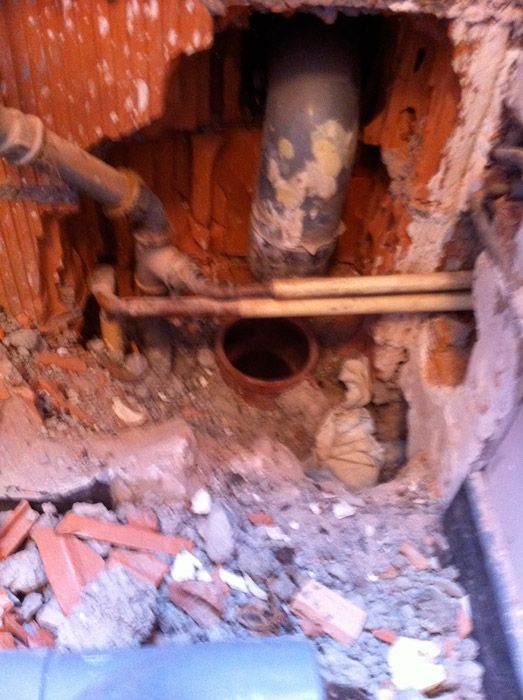 Un trou dans un mur de briques avec des tuyaux qui en sortent.