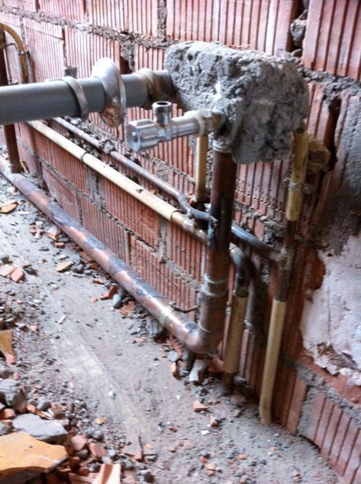 Un mur de briques avec un tas de tuyaux attachés dessus