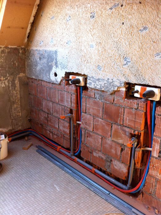 Un mur de briques avec un tas de tuyaux qui en sortent